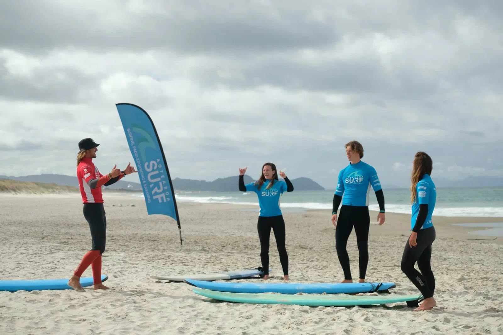 Adult group lesson gathered on the beach with their coach