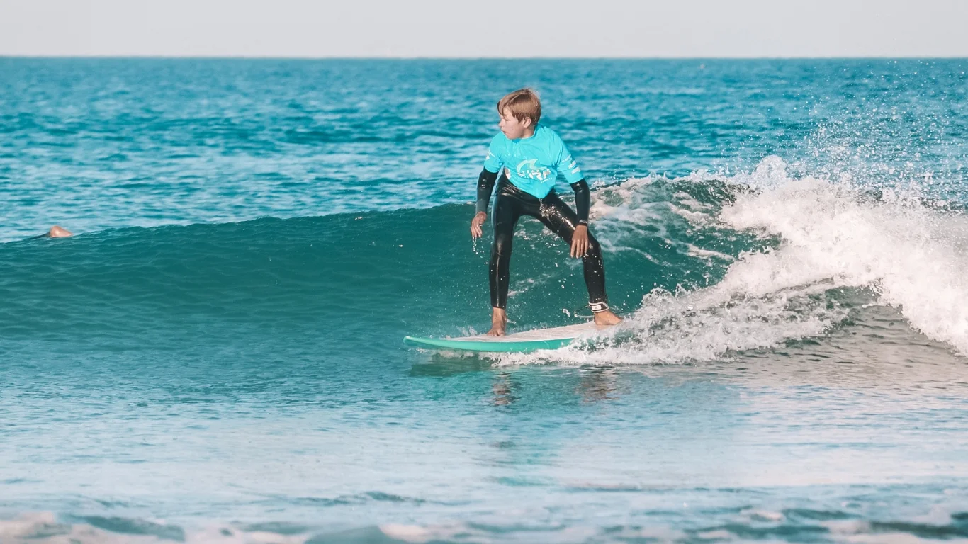 Grom trimming along a clean green wave after school