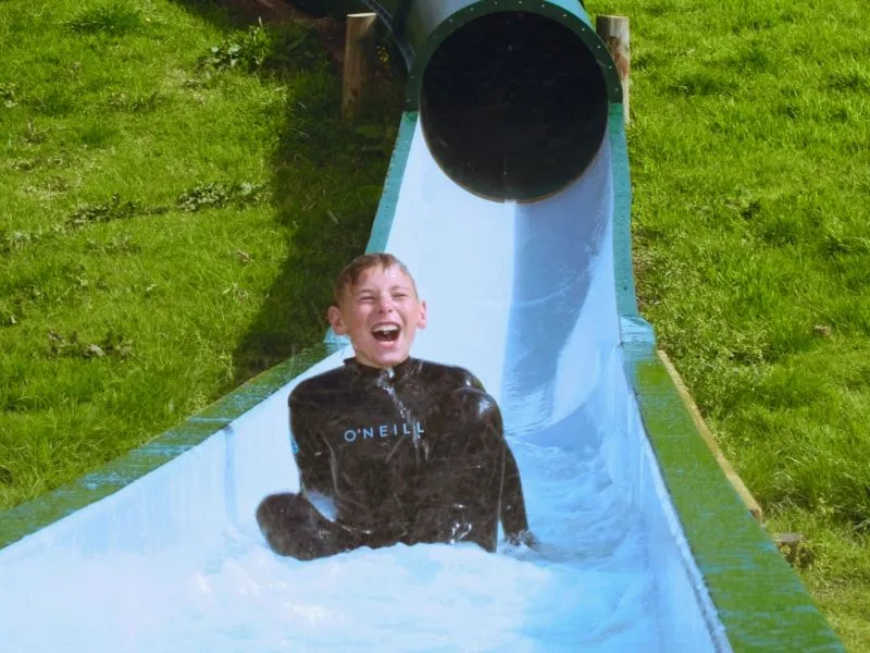 Kid mid laugh flying down the water slide