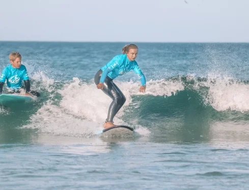 Young surfer trimming a summer program wave in a full wetsuit
