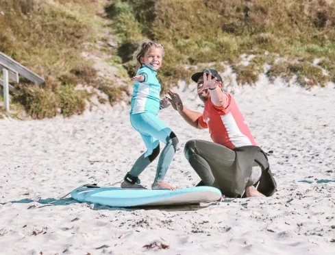Young surfer celebrating with their private coach at Orewa