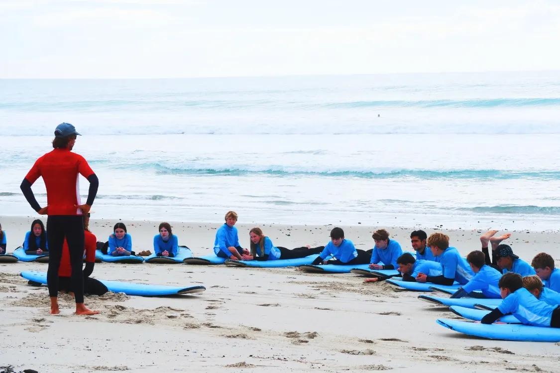 Holiday program kids with boards at Orewa beach