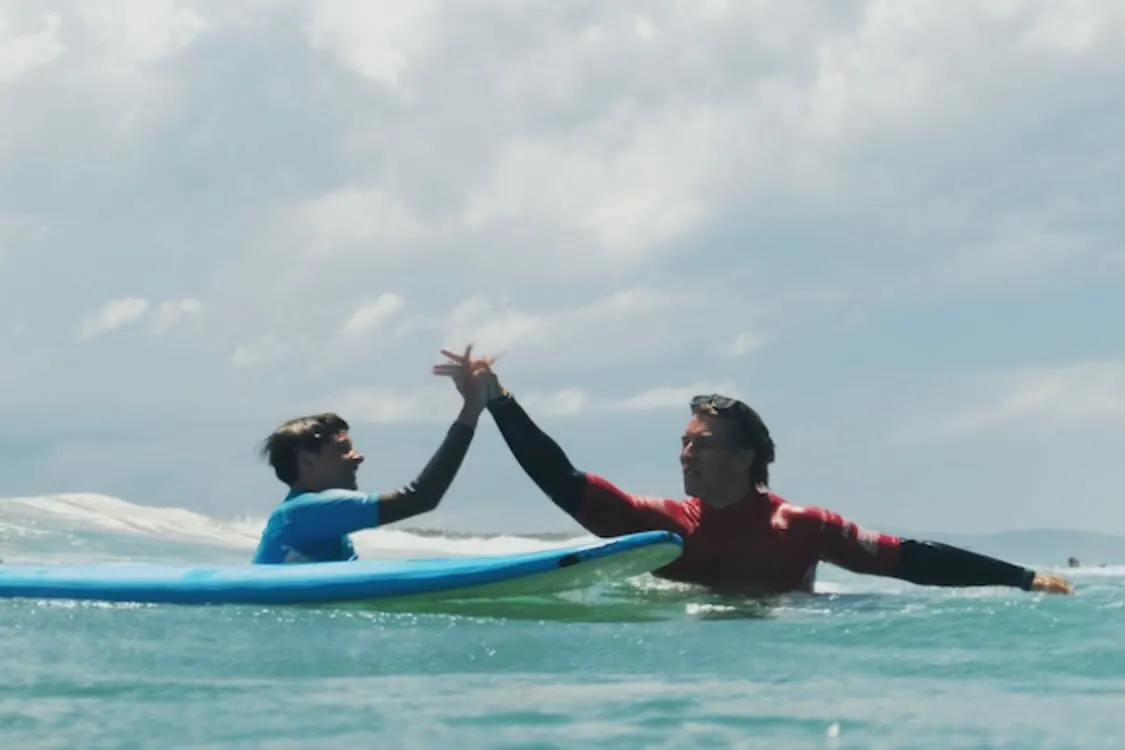 Coach and learner high fiving in the water mid lesson