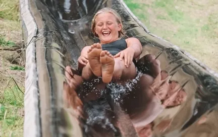 Camper laughing down the water slide at Ultimate camp