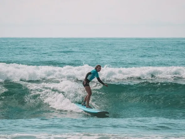 Woman in a blue rash top riding a clean wave